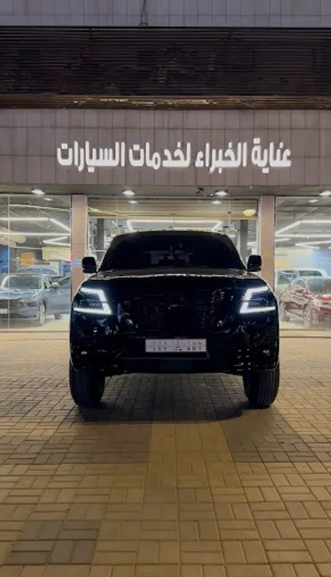سيارة دفع رباعي سوداء من الأمام مواقفة عند مدخل المركز مع ظهور لافتة عناية الخبراء